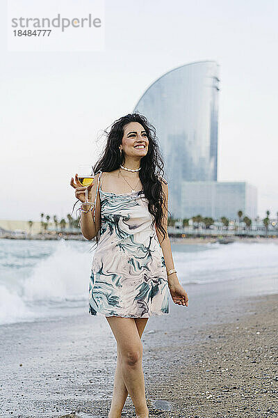 Glückliche Frau hält Weinglas am Strand
