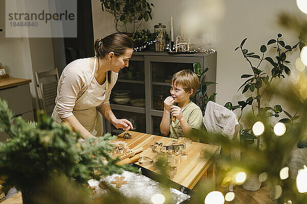 Happy mother and son making Christmas cookies at home