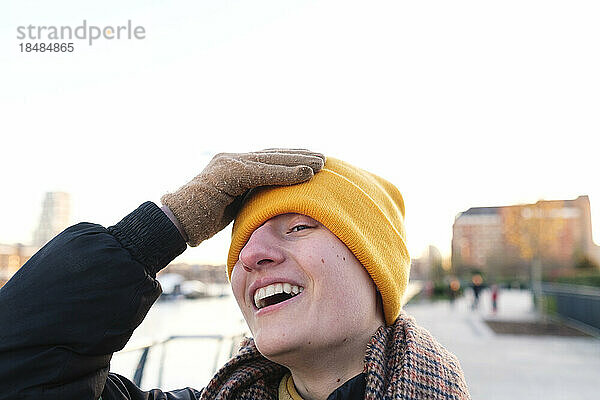 Happy non-binary person wearing yellow knit hat