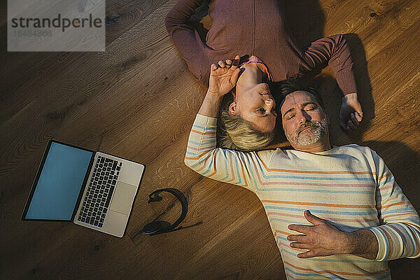 Älteres Paar mit geschlossenen Augen ruht zu Hause auf dem Boden
