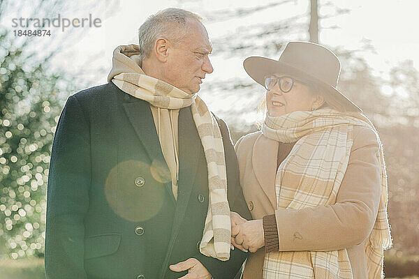 Ältere Frau mit Arm in Arm im Gespräch mit Mann an einem sonnigen Tag