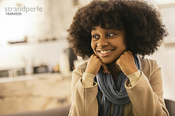 Glückliche junge Frau mit Afro-Frisur sitzt im Café