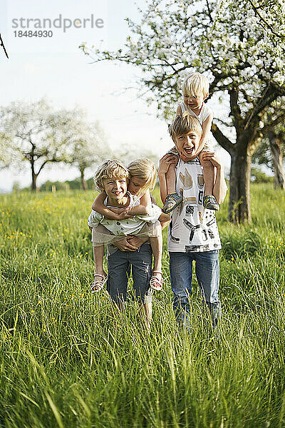 Fröhliche Mädchen und Jungen genießen gemeinsam vor dem Apfelbaum