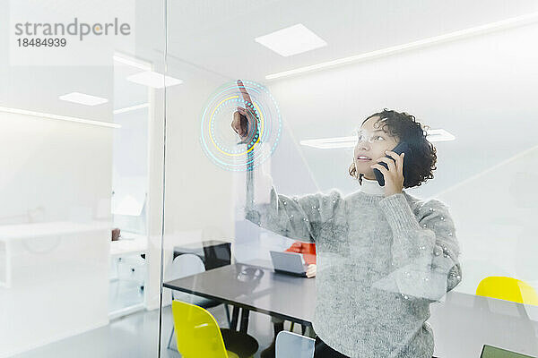 Geschäftsfrau spricht am Arbeitsplatz mit Smartphone und nutzt eine Projektionsglasscheibe