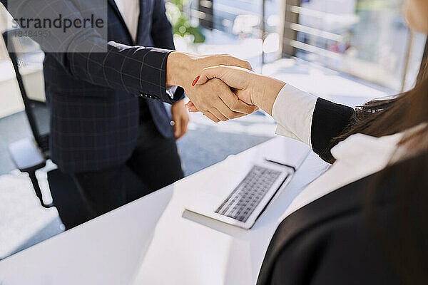 Personalvermittler und Kandidat beim Händeschütteln nach dem Vorstellungsgespräch im Büro