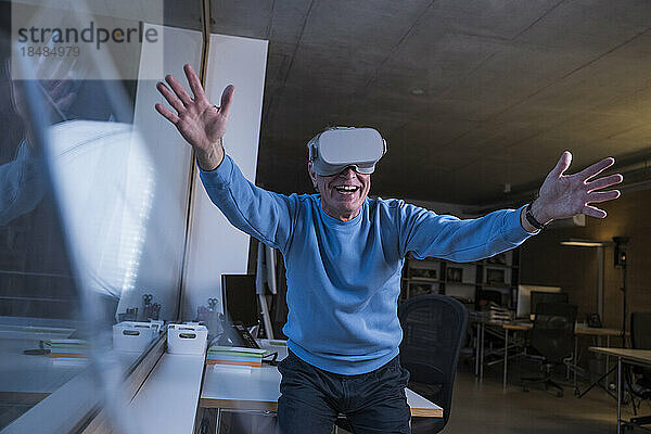 Glücklicher Geschäftsmann mit Virtual-Reality-Headset im Büro