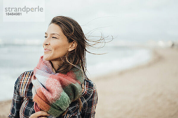 Lächelnde Frau mit Schal am Strand