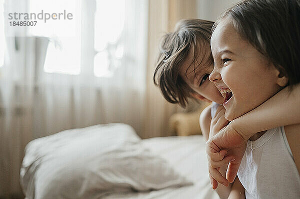 Boy hugging brother on bed at home