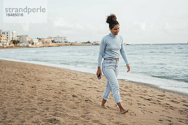 Junge Frau läuft am Strand auf Sand