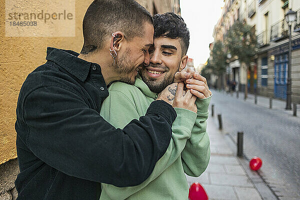 Liebevolles schwules Paar  das sich auf dem Fußweg umarmt