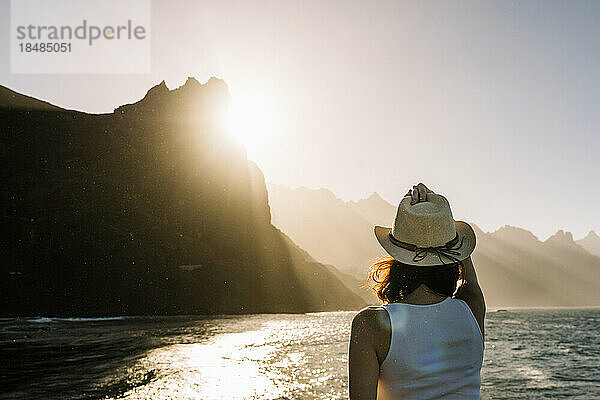 Spain  Canary Islands  Young woman admiring sunset over coastal mountains of Macizo de Anaga range