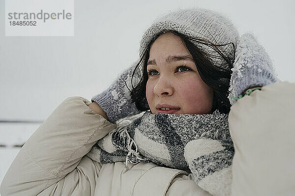 Nachdenkliches Teenager-Mädchen mit Strickmütze und Schal im Winter