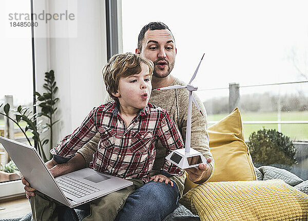 Vater und Sohn blasen zu Hause eine Windkraftanlage