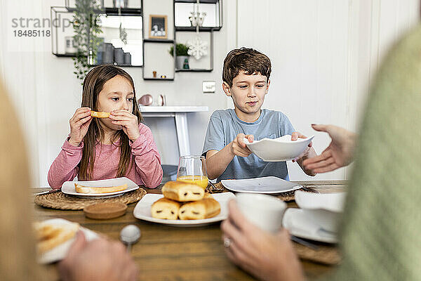 Geschwister mit Mutter und Vater frühstücken gemeinsam zu Hause