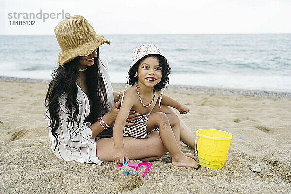 Glücklicher Junge mit Mutter  die im Sand am Strand spielt
