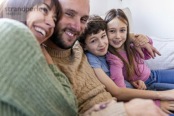 Glückliche Frau umarmt Familie zu Hause auf dem Sofa