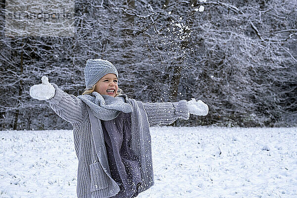 Fröhliches Mädchen in warmer Kleidung  das den Schnee genießt