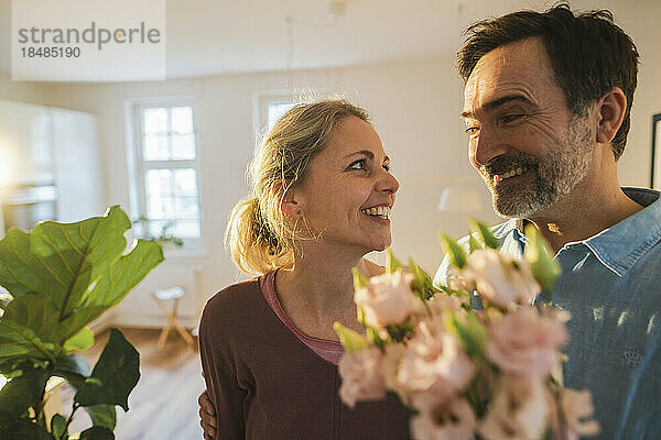 Glücklicher Ehemann überrascht Frau mit Blumen zu Hause