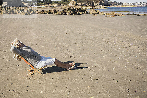 Ältere Frau entspannt sich an einem sonnigen Tag am Strand