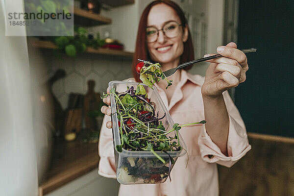 Frau zeigt frischen Salat in der heimischen Küche