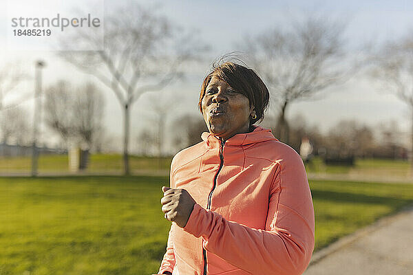 Ältere Frau joggt an sonnigem Tag im Park