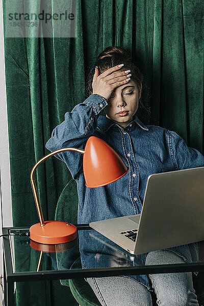 Mädchen mit Kopf in der Hand am Laptop zu Hause