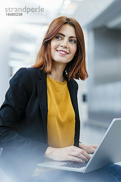 Lächelnde Geschäftsfrau sitzt mit Laptop