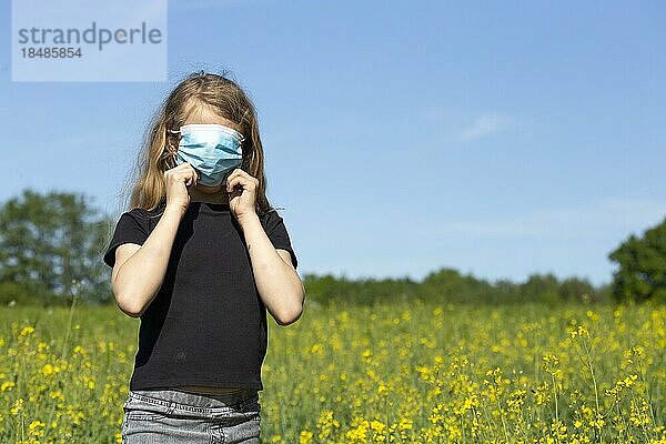 Mädchen (11) mit Mund-Nasen-Schutz  steht im Rapsfeld  Kiel  Schleswig-Holstein  Deutschland  Europa