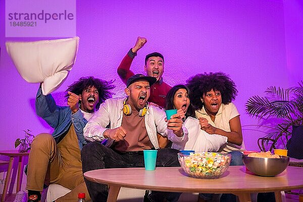 Party für Erwachsene. Junge Leute sitzen auf dem Sofa und schauen ein Fußballspiel mit Popcorn. Emotion für Fußball  lila geführt  ein Tor zu feiern