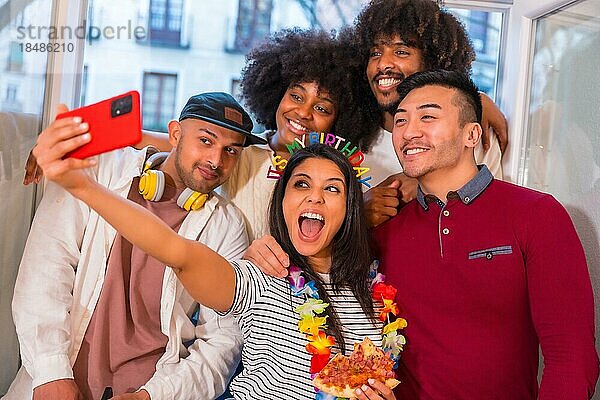 Porträt einer Gruppe von Freunden  die an einem Geburtstag zu Hause auf der Terrasse Pizza essen und ein Selfie als Andenken machen