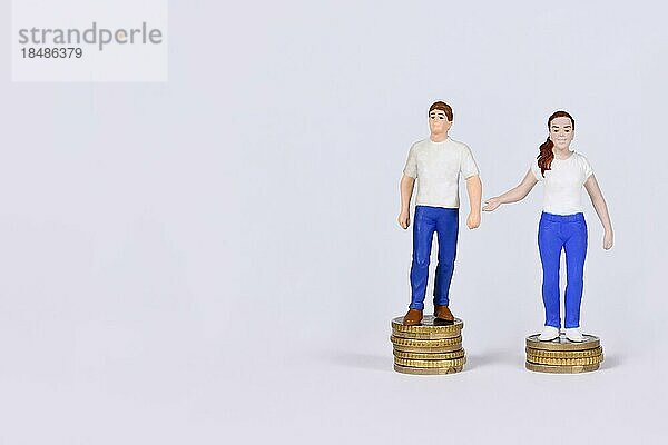 Konzept des geschlechtsspezifischen Lohngefälles mit einem Mann und einer Frau  die auf einer unterschiedlichen Anzahl von Münzen mit Kopierraum stehen