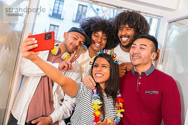 Porträt einer Gruppe von Freunden  die an einem Geburtstag zu Hause auf der Terrasse eine Pizza essen und lächelnd ein Erinnerungs Selfie machen