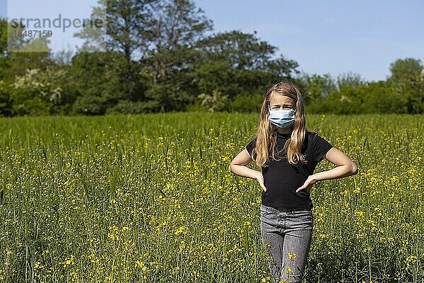 Mädchen (11) mit Mund-Nasen-Schutz  steht im Rapsfeld  Kiel  Schleswig-Holstein  Deutschland  Europa