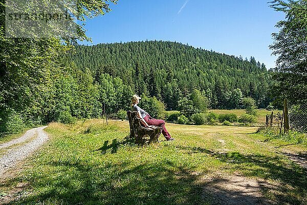 Frau sitzt auf Bank und schaut auf den Wald auf dem Wanderweg Sprollenhäuser Hut  Bad Wildbad  Schwarzwald  Deutschland  Europa