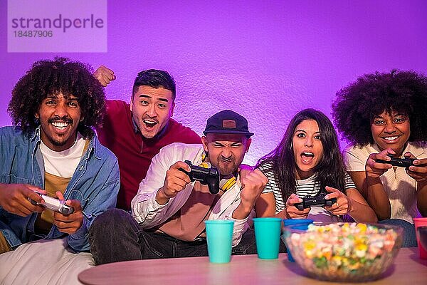 Party für Erwachsene. Attraktive junge Männer sitzen auf dem Sofa und spielen Videospiele mit Popcorn. Mit dem Joystick oder Controller in der Hand und Blick auf den Monitor