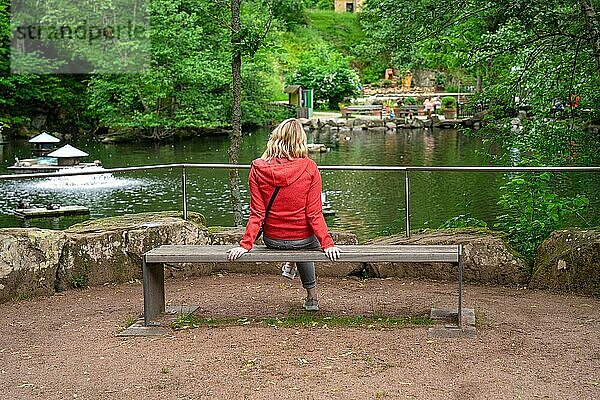 Frau sitzt auf Bank vor Teich im Kurpark  Bad Wildbad  Schwarzwald  Deutschland  Europa