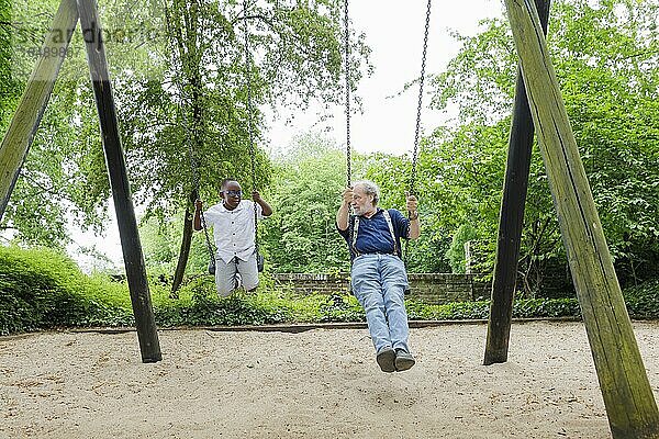 Großeltern auf Zeit. Großvater schaukelt mit seinem Schützling auf einem Spielplatz.  Bonn  Deutschland  Europa