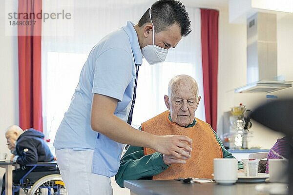 Pfleger hilft einem Mann zu trinken im Pflegeheim  Heidelberg  Deutschland  Europa
