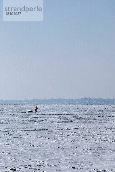 Harrison Township  Michigan  Ein Eisfischer schleppt seine Ausrüstung über die gefrorene Oberfläche des Lake St. Clair im Lake St. Clair Metropark
