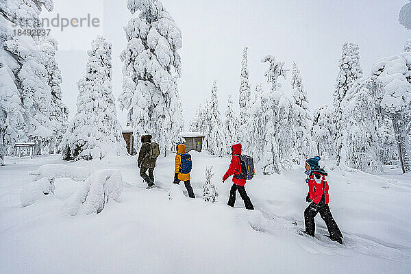 Glückliche Familie beim Spaziergang im verschneiten Wald  Iso Syote  Nördliches Ostbottnien  Lappland  Finnland  Europa