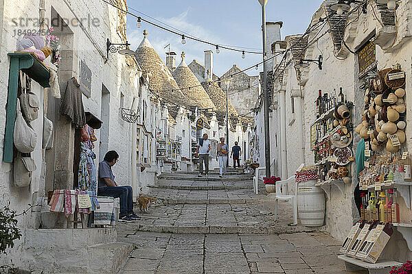 Weiß getünchte Trulli-Häuser und Souvenirläden entlang der Straße in der Altstadt  Alberobello  UNESCO-Weltkulturerbe  Apulien  Italien  Europa