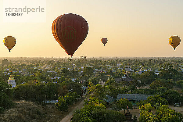 Heißluftballons bei Sonnenaufgang über einem Dorf in der Nähe von Bagan (Pagan)  Myanmar (Burma)  Asien