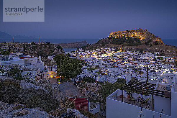 Blick auf Lindos und die Akropolis von Lindos aus erhöhter Position in der Abenddämmerung  Lindos  Rhodos  Dodekanes Inselgruppe  Griechische Inseln  Griechenland  Europa