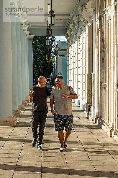 Zwei gute Freunde gehen eine Kolonnade entlang  Cienfuegos  Kuba  Westindien  Karibik  Mittelamerika