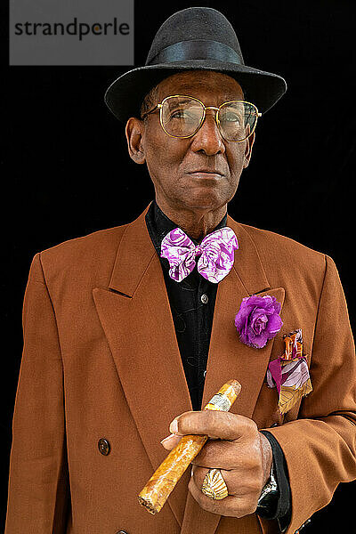 Stehender Mann  gekleidet als Dandy oder Gangster der 1950er Jahre mit Filzhut und großer Zigarre  Havanna  Kuba  Westindien  Karibik  Mittelamerika