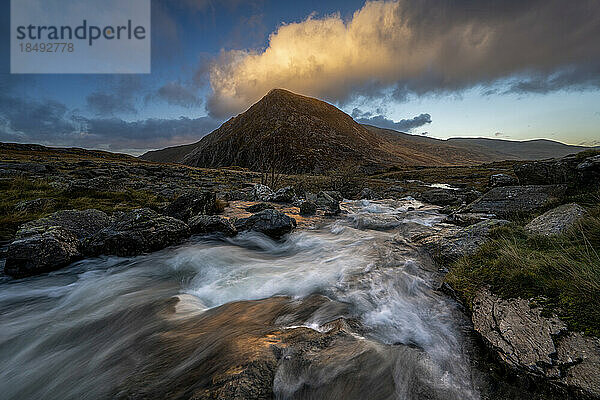 Wasser  das über einen Wasserfall in Richtung Llyn Dinas mit einer Bergkette im Hintergrund stürzt  Snowdonia  Wales  Vereinigtes Königreich  Europa