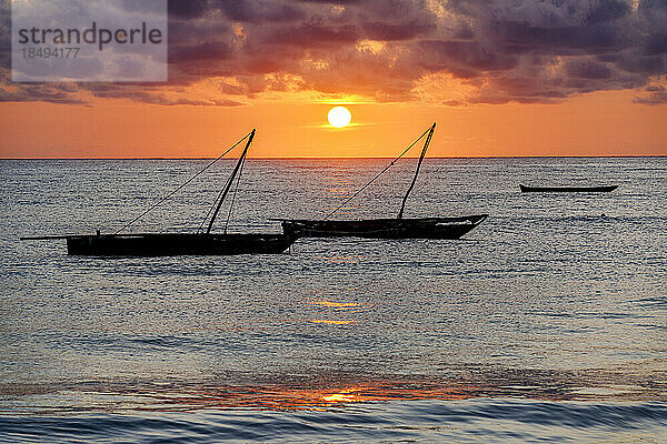 Bewölkter Himmel bei Sonnenaufgang über Silhouetten von im Meer vertäuten Booten  Jambiani  Sansibar  Tansania  Ostafrika  Afrika