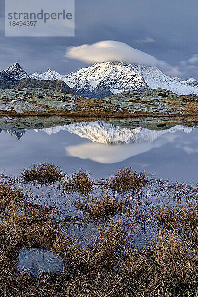 Schneebedeckte Gipfel spiegeln sich in einem Teich im Herbst  Alpe Fora  Valmalenco  Valtellina  Provinz Sondrio  Lombardei  Italien  Europa