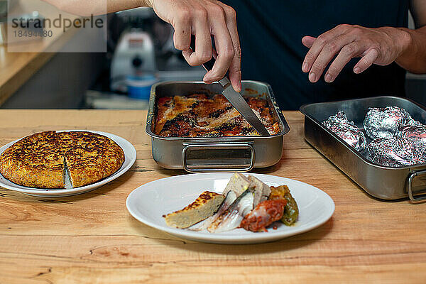 Ein Mann bereitet Speisen und Teller mit italienischem Essen auf der Küchentheke eines Restaurants zu.