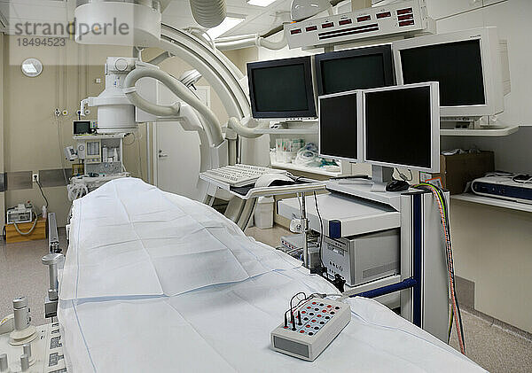 Ein modernes Krankenzimmer  ein großes tragbares mobiles Scangerät mit gebogenen Armen und Bildschirmreihen für die medizinische Bildgebung.